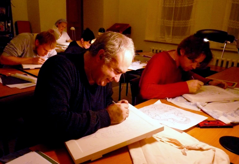 a man sitting at a table while writing on a notepad