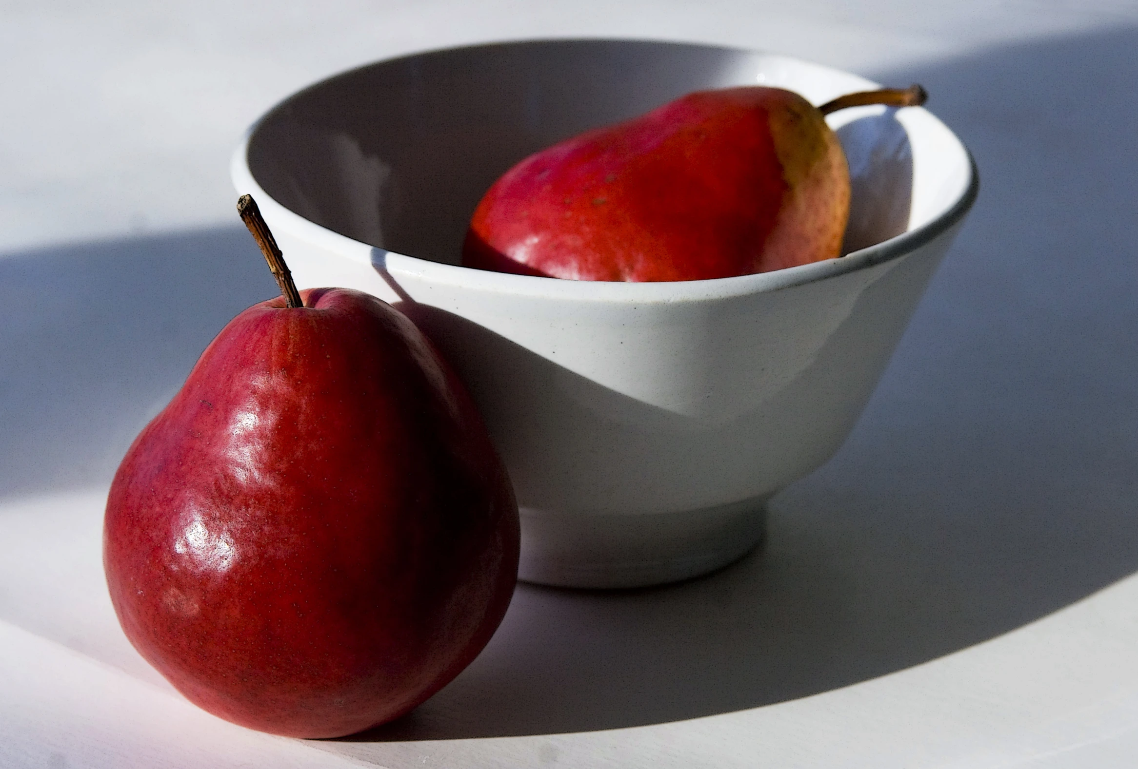 two ripe apples and a whole red apple in a bowl