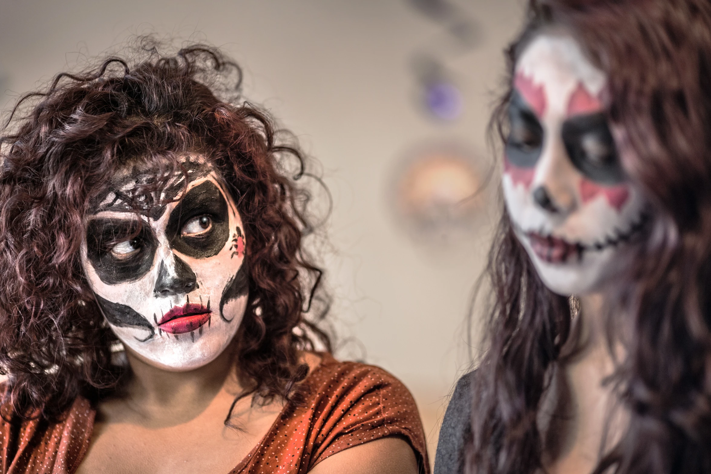 two women in face paint on their faces looking at the camera