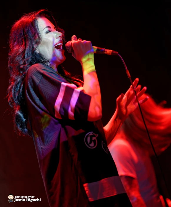 a woman holding a microphone in her hand and singing