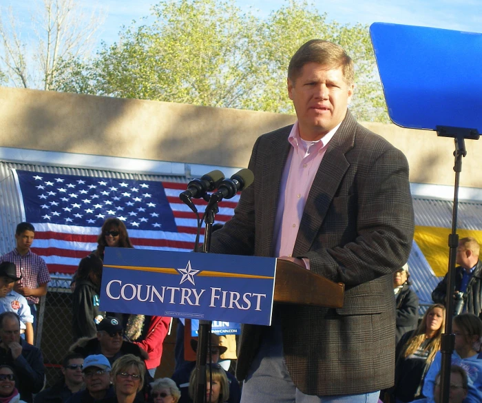 man standing at podium giving a speech in front of a crowd