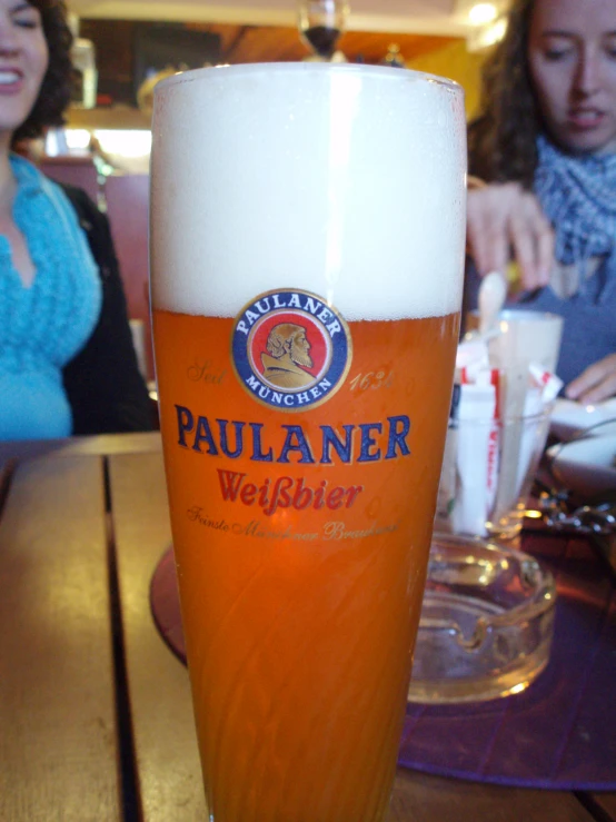 two women are sitting around a beer glass