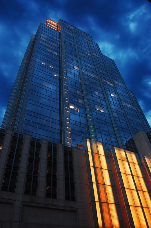 an upward view of the face of a glass skyscr