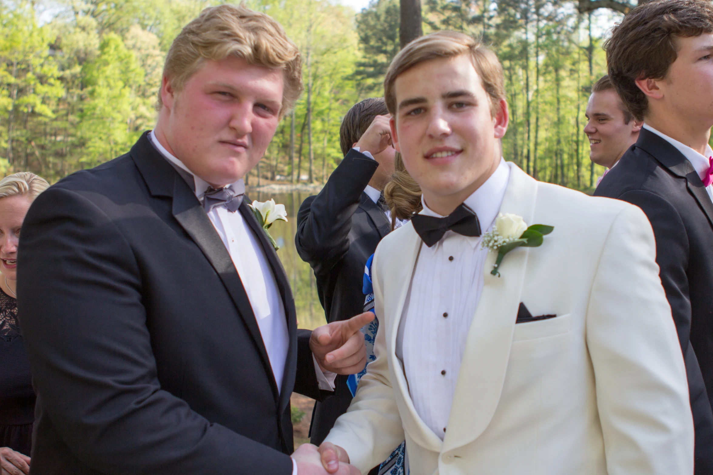 two young men in tuxedos having some fun together