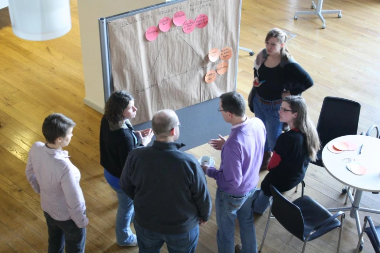 several people are talking at a table in a room with several chairs