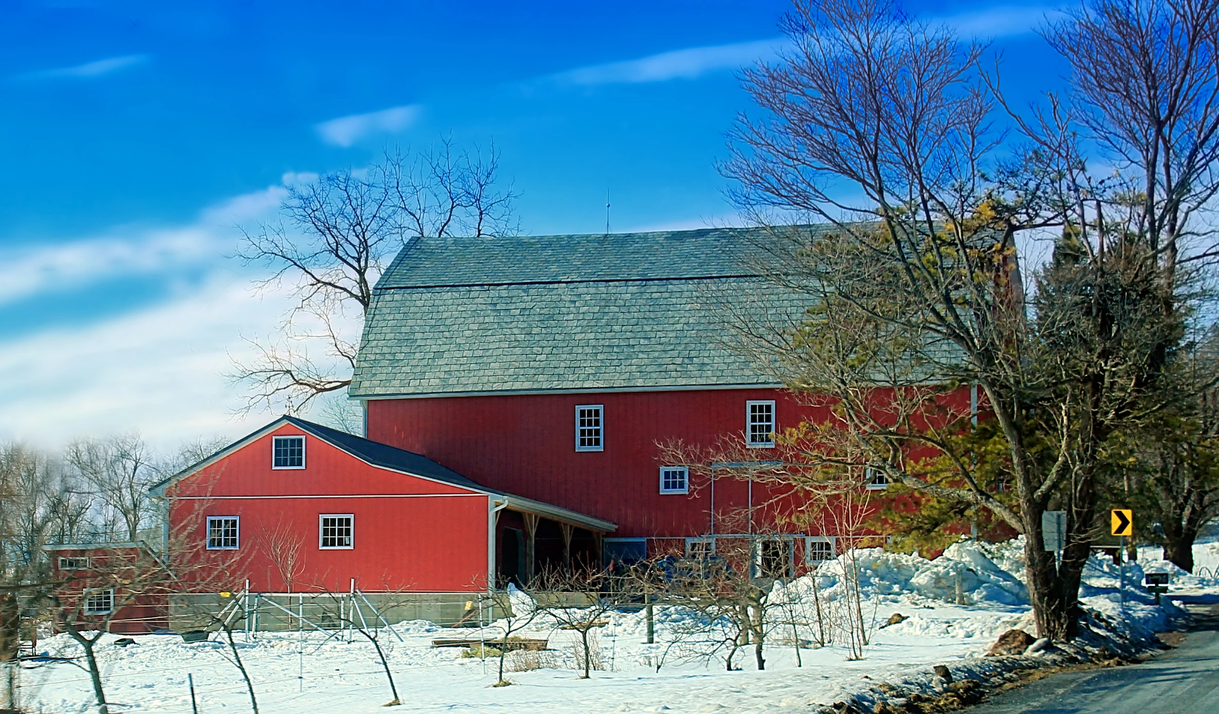 a barn sitting next to a road in the winter