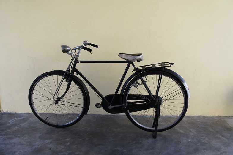 a black bicycle leans against the wall