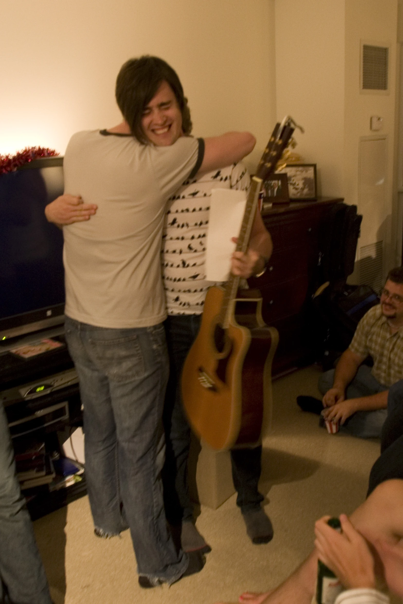 a man holding his guitar in a house