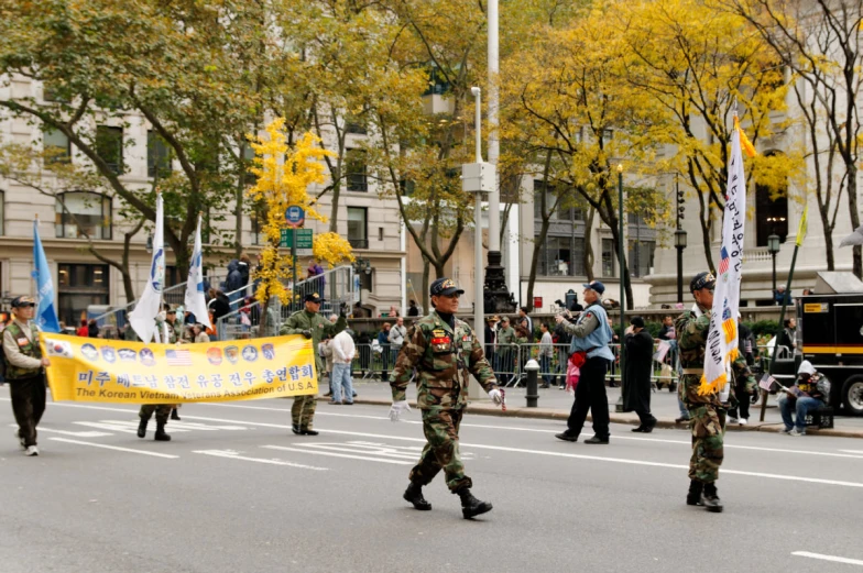 two soldiers walk through a street holding flags