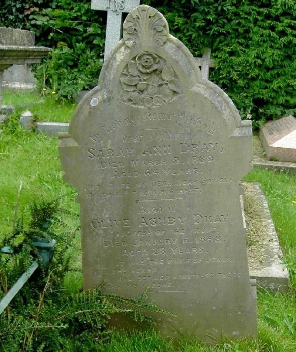 a headstone in the grass near a cemetery
