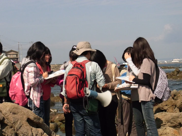 many students standing near the rocks near the ocean