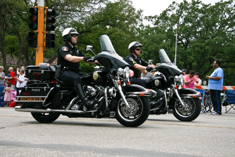 two police officers riding on their motorcycles in front of the crowd