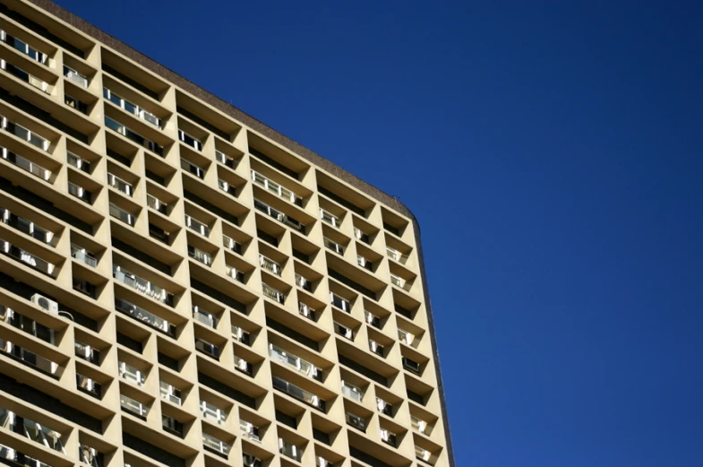 tall building with windows and balconies against a blue sky