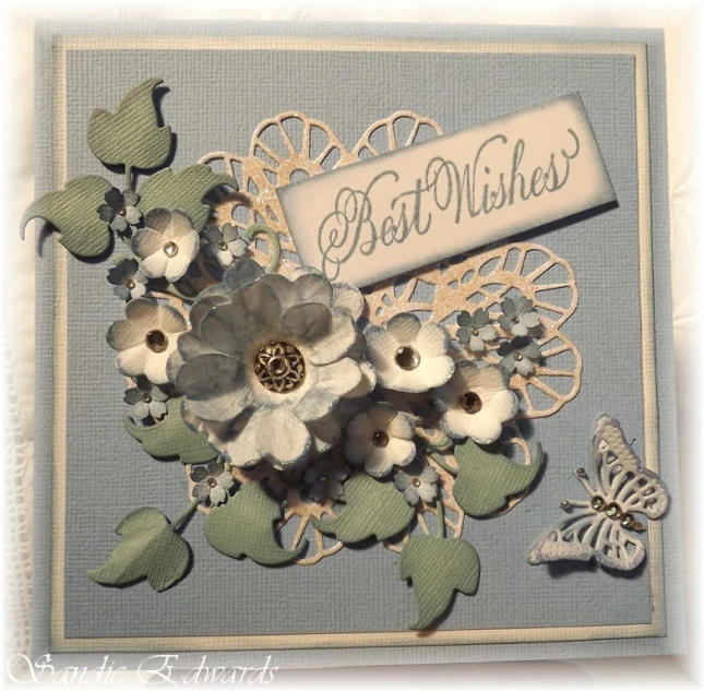 an altered card featuring blue and white flowers with the words best wishes on it