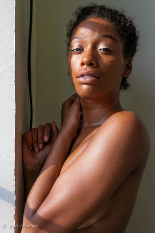 a woman with dark skin and white teeth standing by a wall