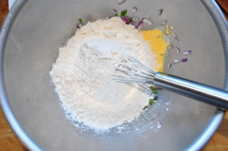 a mixing bowl with white food and flour next to a fork