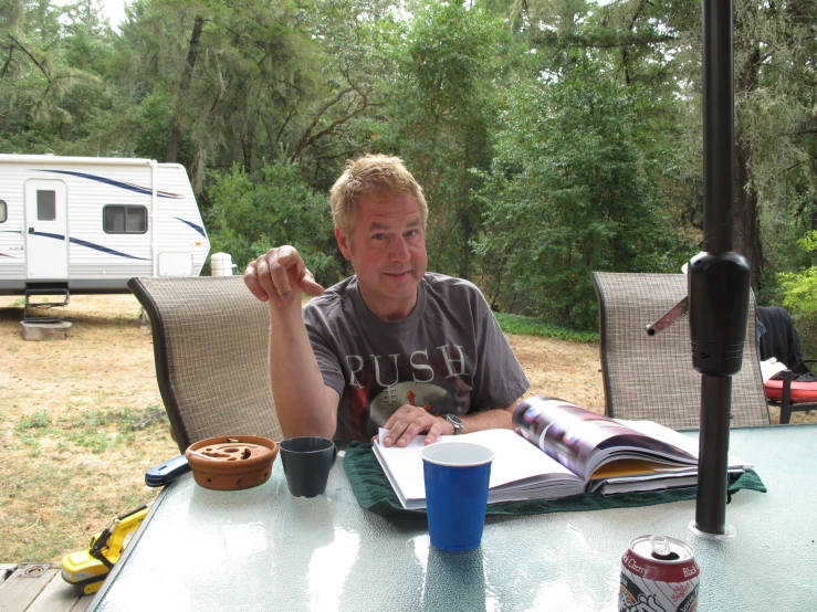 a man sitting at a table next to an open book and coffee