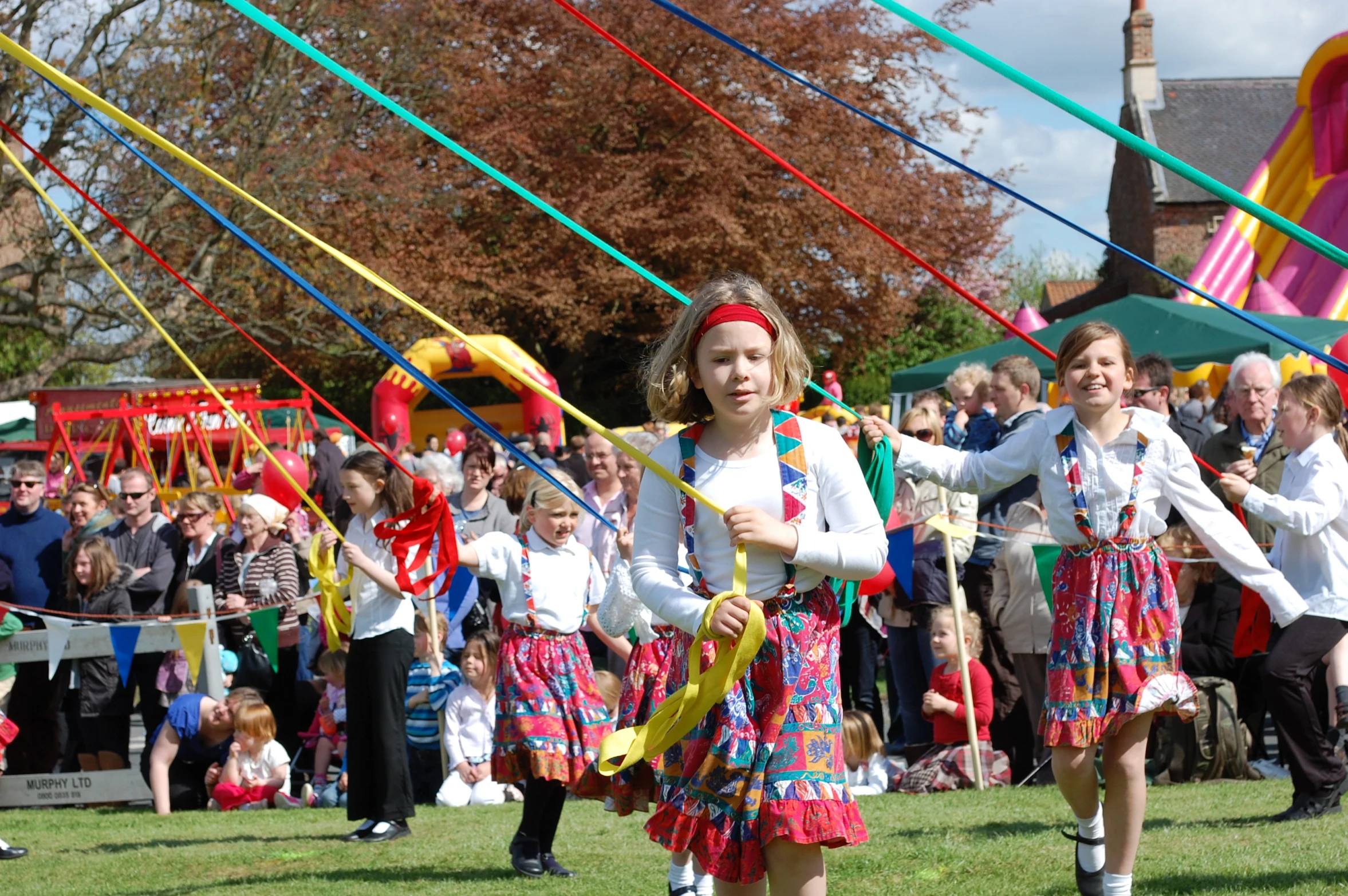 two girls in colorful costumes holding streamers with adults watching