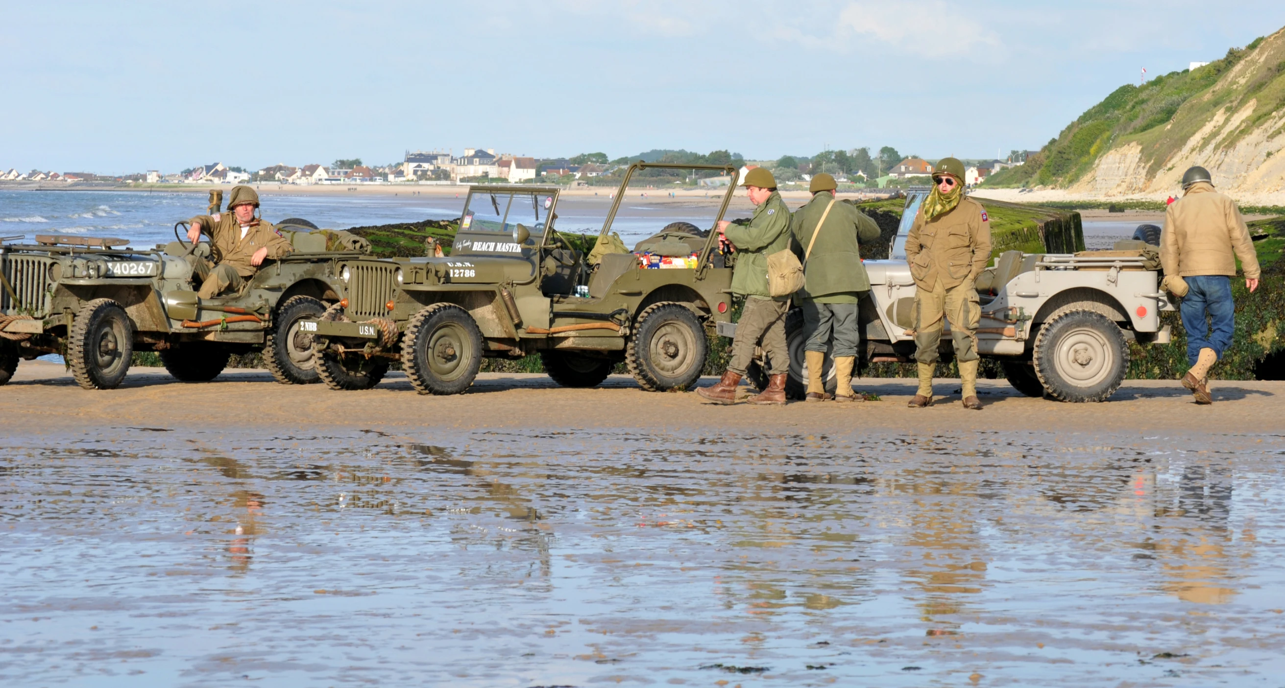 people standing in the water next to several vehicles