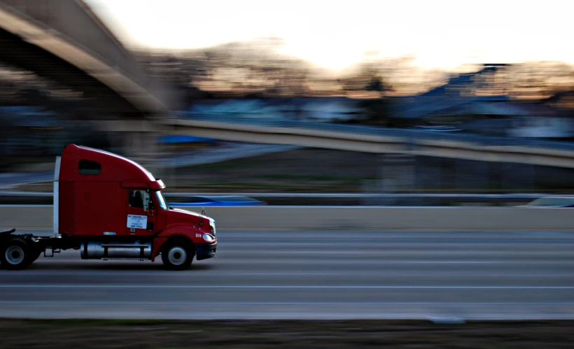 a red semi truck moving down a highway