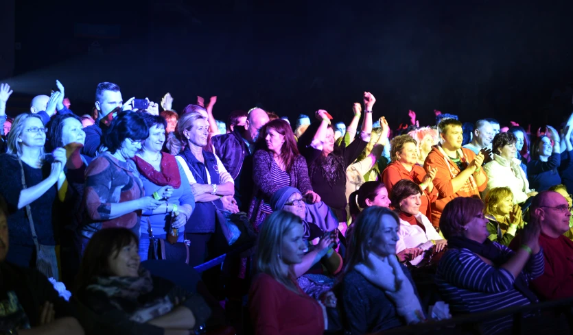 a large group of people are seated in the dark watching an event