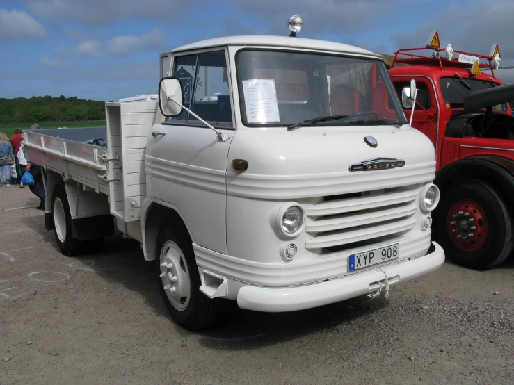 an old white truck parked next to a red truck