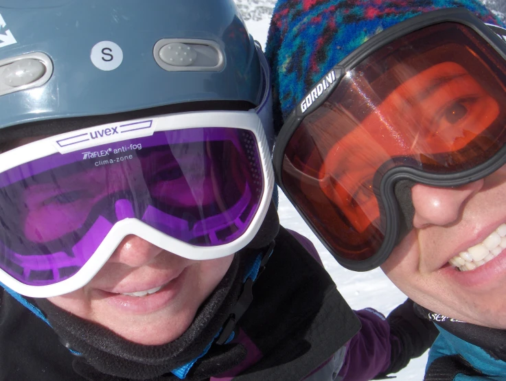 two people standing next to each other wearing ski equipment