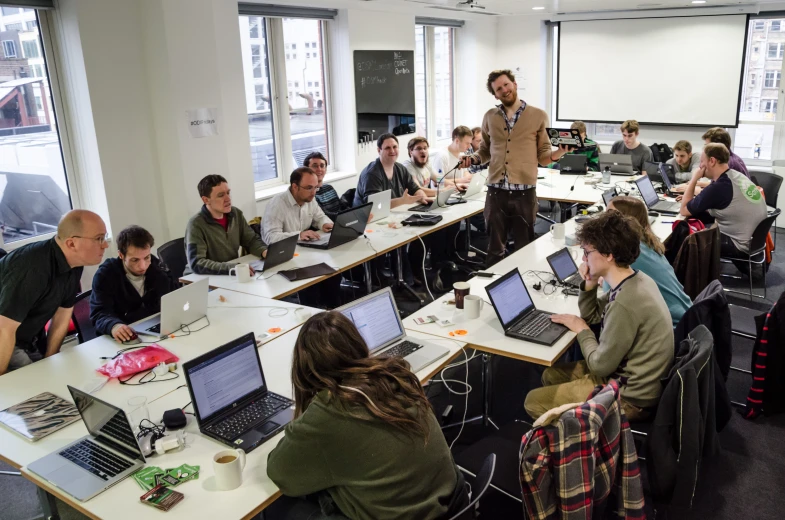 an office filled with students working on laptops