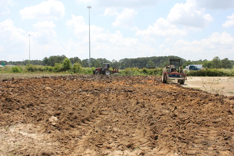 there is a farm field with two plow trucks