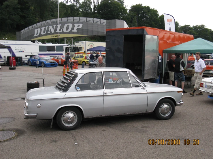 a vintage car is parked at a small parking spot with people around it