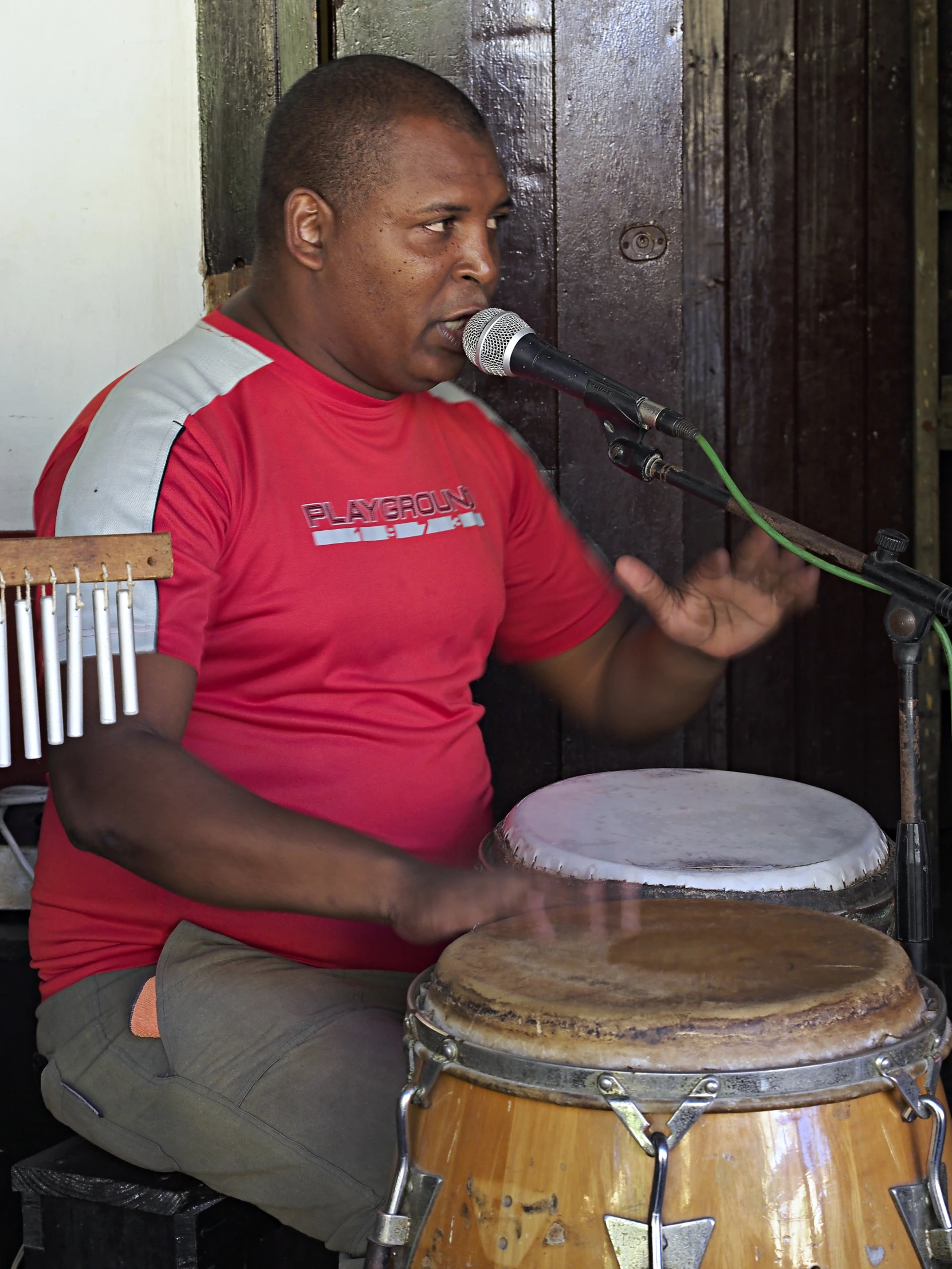 a man is playing a song while sitting near a wooden drum