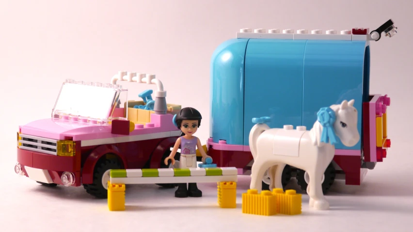 a toy horse standing in front of a lego truck with a trailer