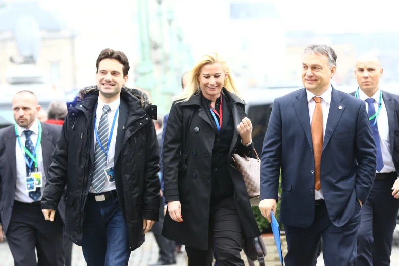 three people are walking on the street holding onto leashes