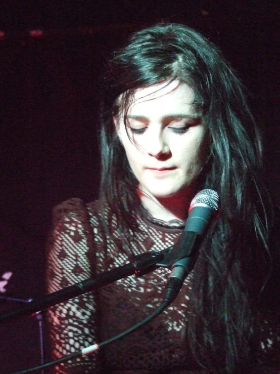 a woman standing next to a microphone with long hair