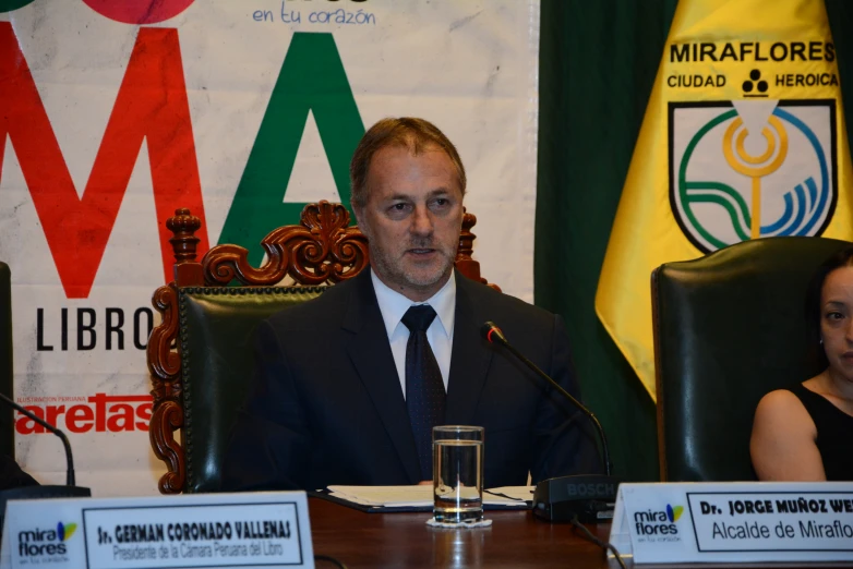 a man sits in front of three microphones and speaks