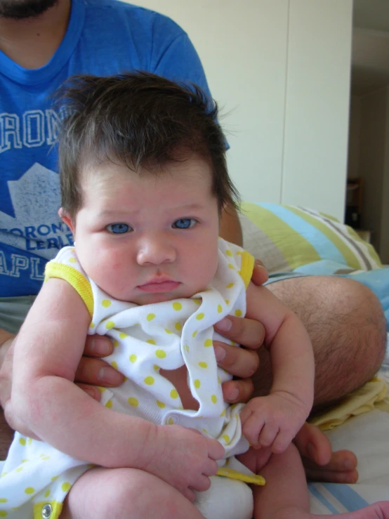 a baby sits on his parent's lap and holds the infant