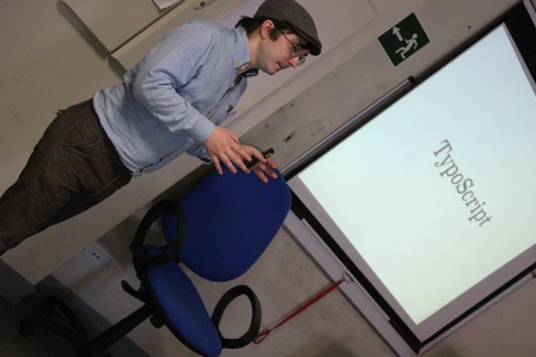 a man standing in front of a projector screen talking on his cell phone