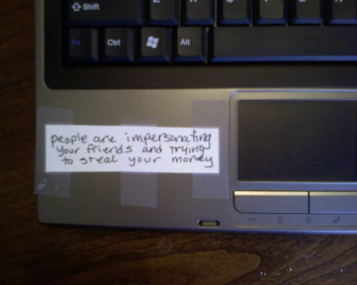 a note written on a laptop keyboard, indicating that people are impersoning