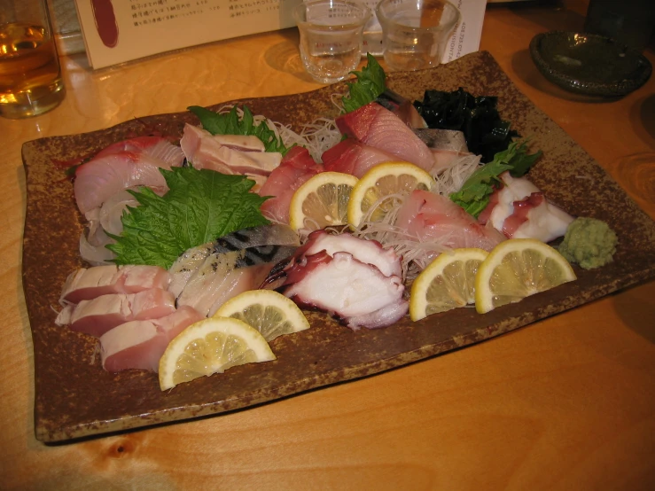 several raw foods on wooden platter with drinks in background