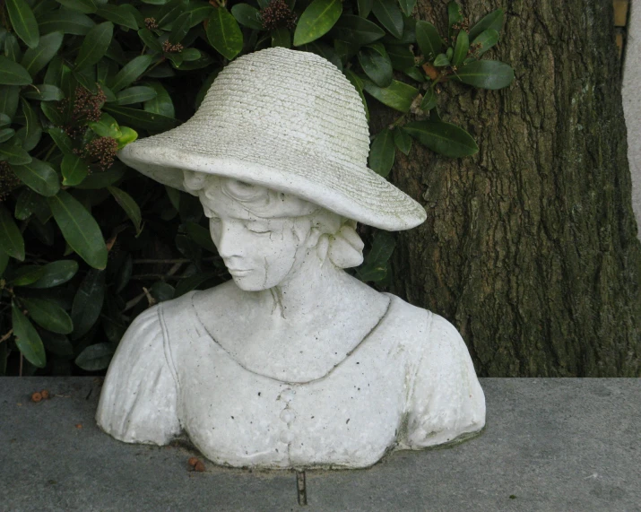 an outdoor white statue with a large straw hat on it