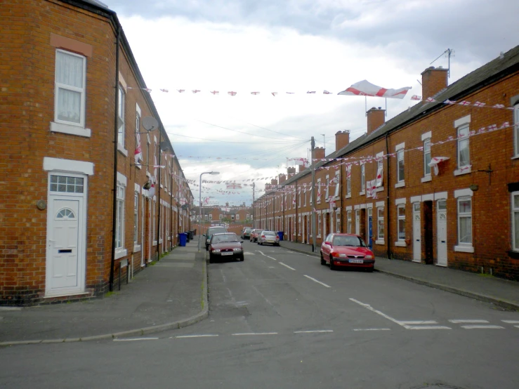 a street with cars parked next to red brick houses
