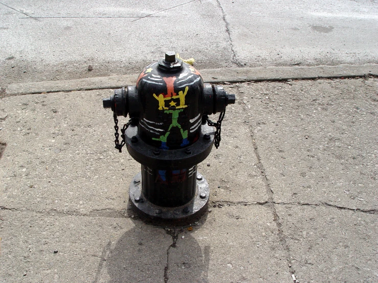 a black fire hydrant on the corner of a street