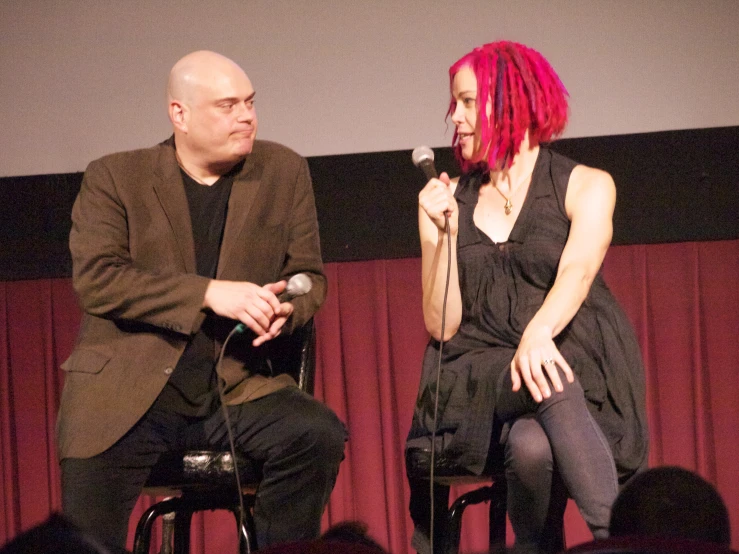 a man and woman are talking while they hold a microphone
