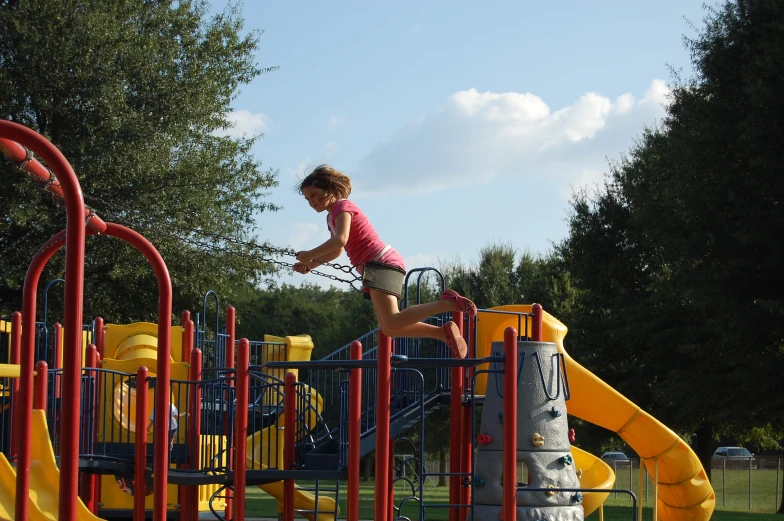 a little girl playing at a playground while onlookers watch