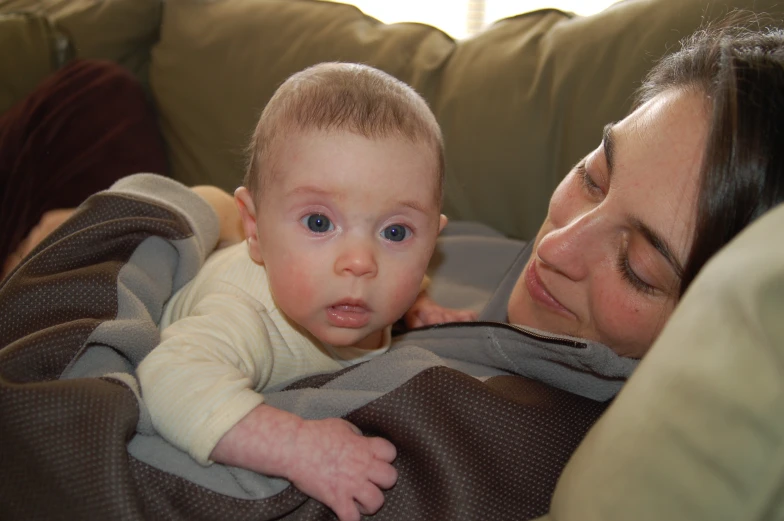 a woman is holding a baby who is wrapped in a blanket