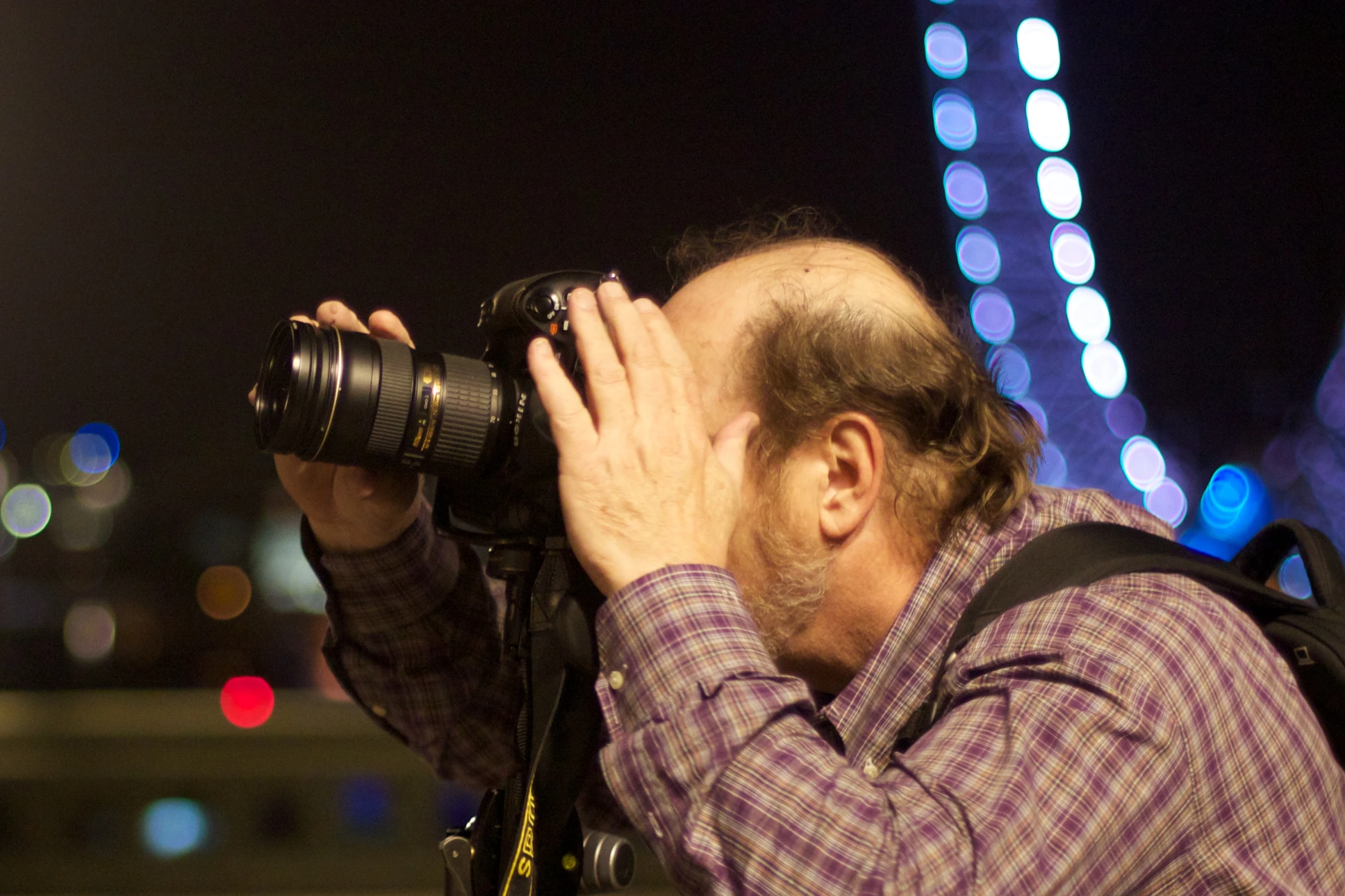 a man holding a camera next to a very large tower