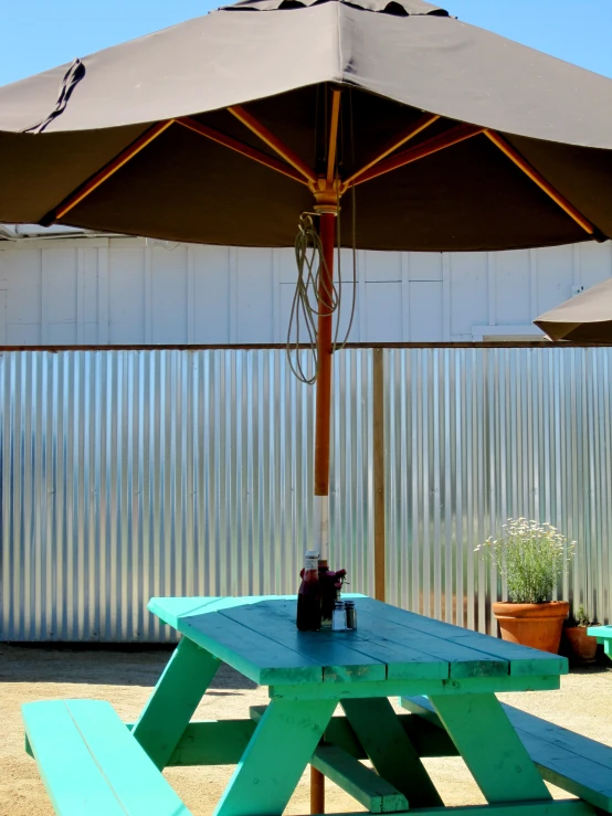 two beer mugs and a bottle under an umbrella