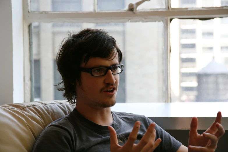 a man in a gray shirt sitting on a couch