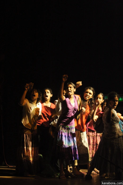 a group of girls standing together while holding hands in the air