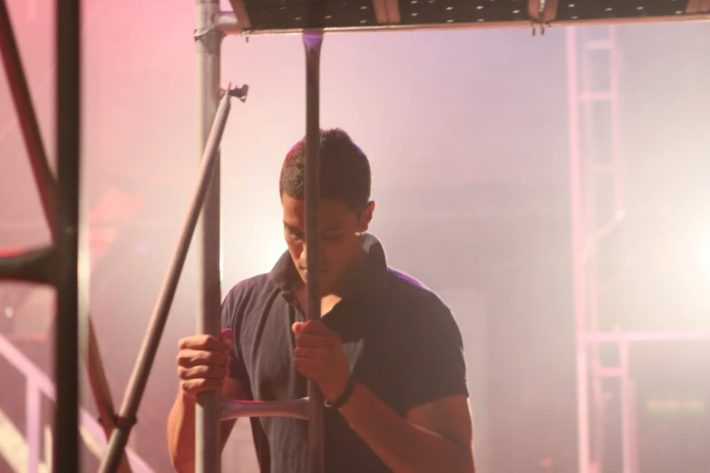 a man in blue shirt standing by a pole